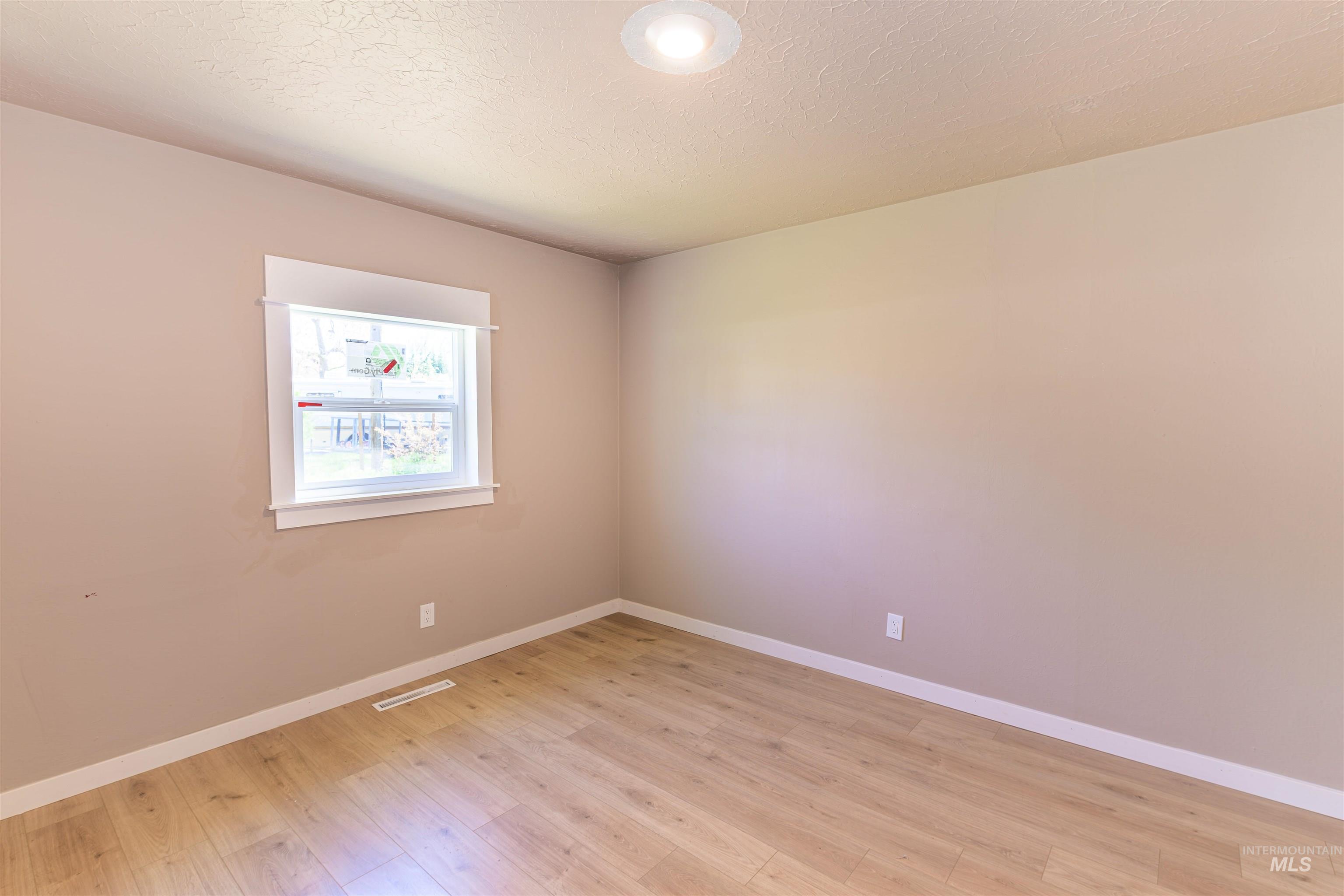 2003 North Cole Road Boise, ID 83704 - Photo 22 of 40 Empty room with light wood finished floors and a textured ceiling