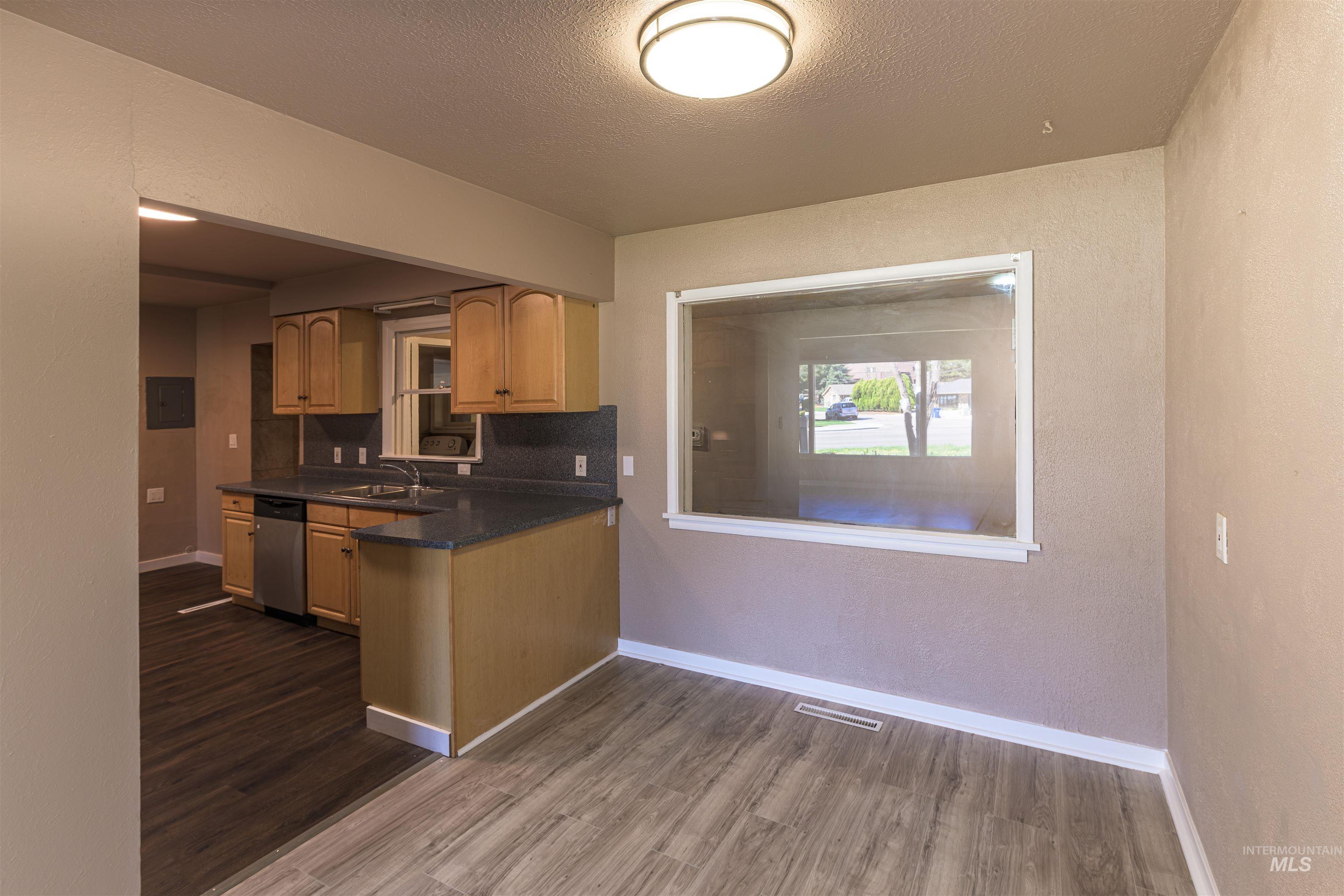 2003 North Cole Road Boise, ID 83704 - Photo 6 of 40 Kitchen featuring dark wood-style flooring, a textured ceiling, tasteful backsplash, dishwasher, and a textured wall