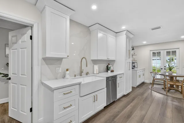 a kitchen with stainless steel appliances a dining table chairs and wooden floor