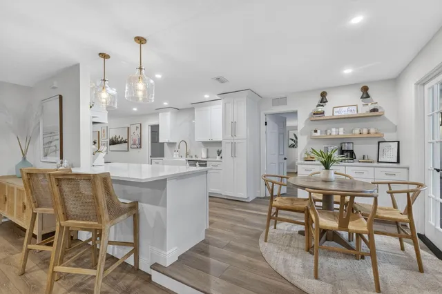 a living room with furniture kitchen view and a wooden floor