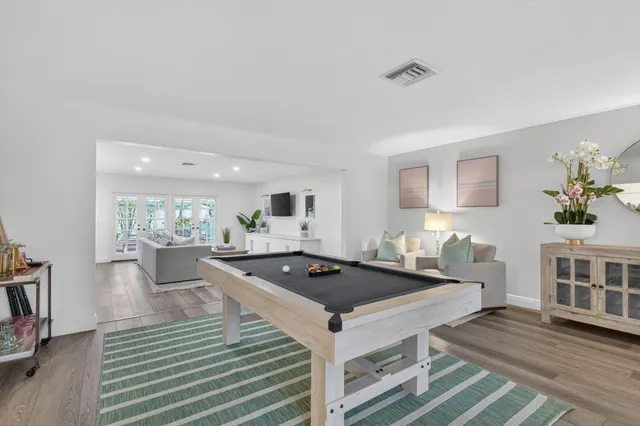 a kitchen with stainless steel appliances granite countertop a stove a sink dishwasher and white cabinets with wooden floor