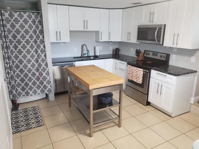 a kitchen with stainless steel appliances a stove a sink a microwave and cabinets