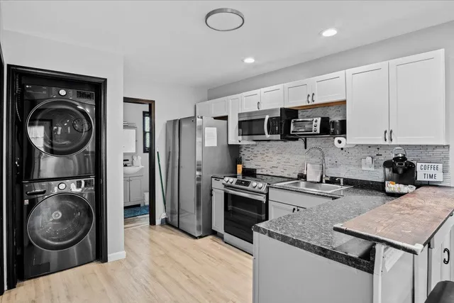 a kitchen with stainless steel appliances granite countertop a sink a stove a washer and dryer