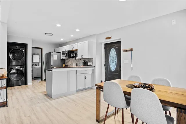 a kitchen with stainless steel appliances granite countertop a kitchen island a stove a refrigerator a sink a dining table and chairs