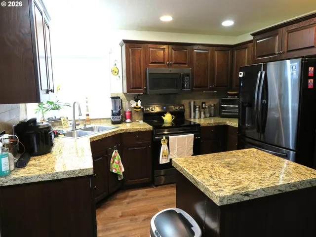 a kitchen with kitchen island granite countertop wooden cabinets and a refrigerator