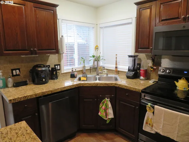 a kitchen with granite countertop a sink stainless steel appliances and cabinets