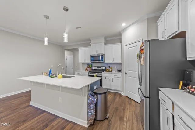 a kitchen with stainless steel appliances granite countertop a stove top oven a sink a dining table and chairs with wooden floor