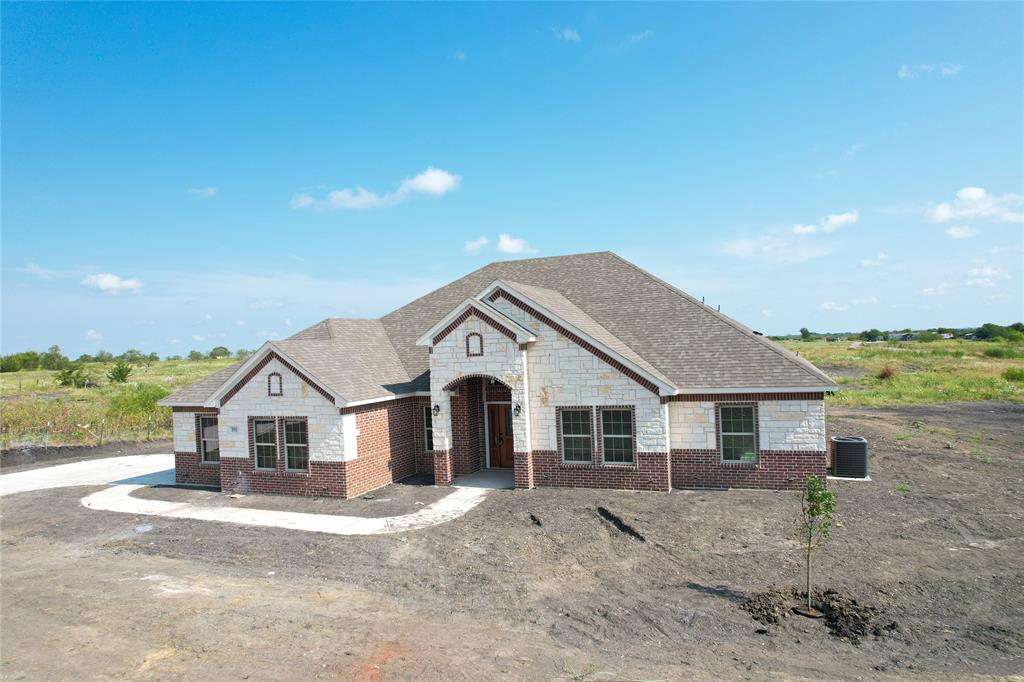 French country home featuring cooling unit, brick siding, roof with shingles, and stone siding