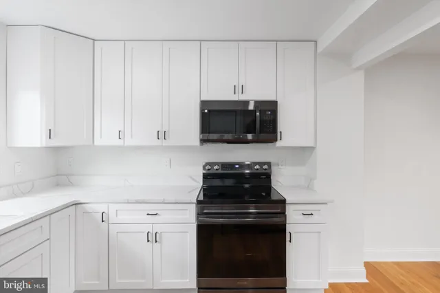 a kitchen with white cabinets and black appliances