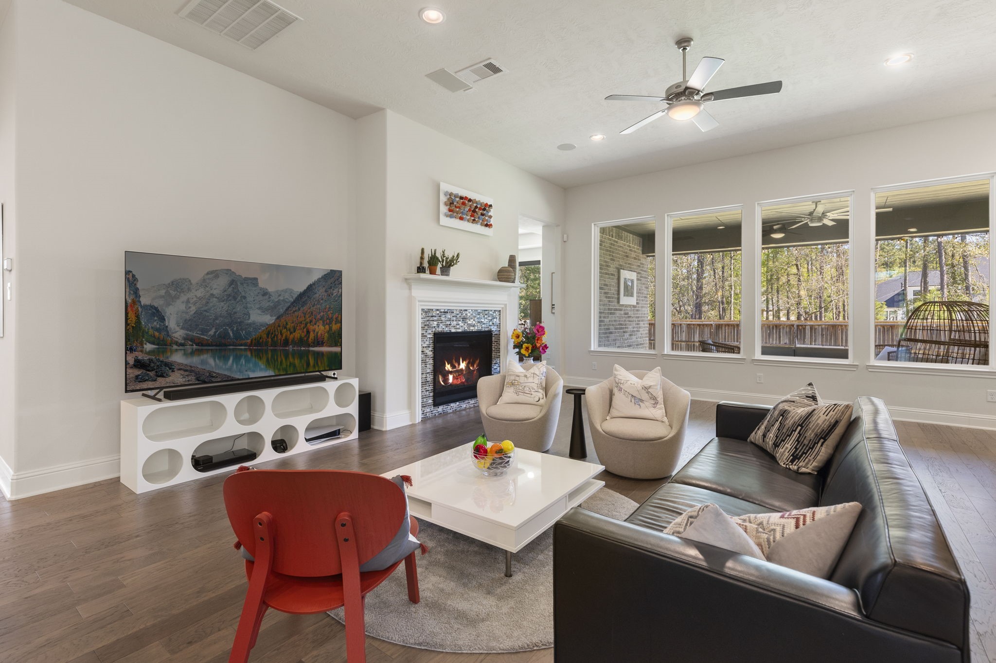 4115 Flagstone Pine Lane Spring, TX 77386 - Photo 6 of 40 The family room is a true showstopper, featuring a soaring ceiling that adds a sense of grandeur and a breathtaking wall of windows that perfectly frame the tranquil views of the serene backyard. Sunlight pours into the space, creating a warm and inviting atmosphere throughout the day. The built-in surround sound system elevates the experience, providing seamless audio for entertaining guests, whether hosting lively gatherings or enjoying a quiet evening with friends.