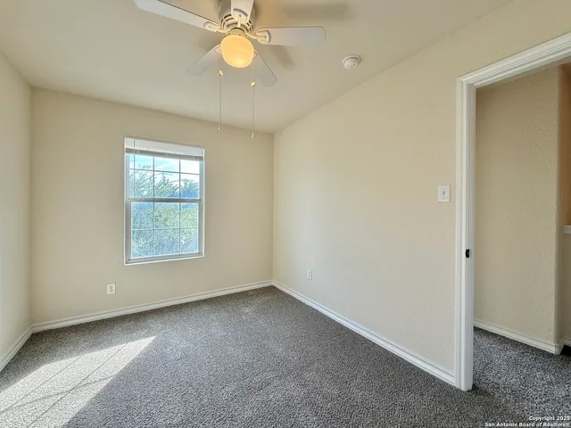 an empty room with a chandelier fan and windows