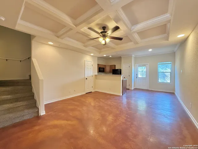 a view of a livingroom with a kitchen island wooden floor and a ceiling fan