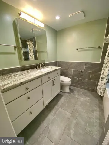 a bathroom with a granite countertop sink a toilet and a mirror