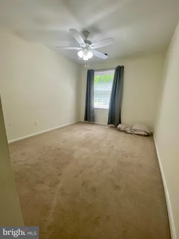 an empty room with a ceiling fan and window