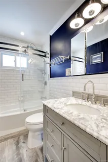 a bathroom with a granite countertop sink a toilet a mirror and bathtub