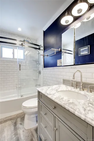 a bathroom with a granite countertop sink a toilet a mirror and bathtub