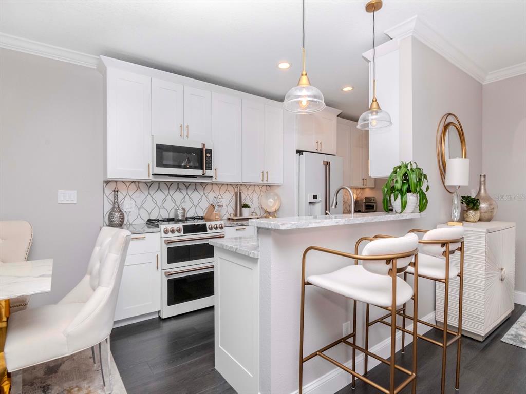2807 West Hawthorne Road, Unit 11 Tampa, FL 33611 - Photo 6 of 76 a kitchen with kitchen island a stove a microwave a sink a stove and a dining table with wooden floor