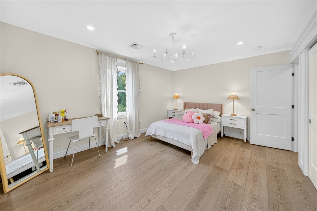 738 Smith Neck Road Dartmouth, MA 02748 - Photo 36 of 42 a spacious bedroom with a bed and a chandelier