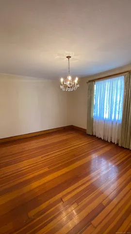 an empty room with wooden floor chandelier fan and windows