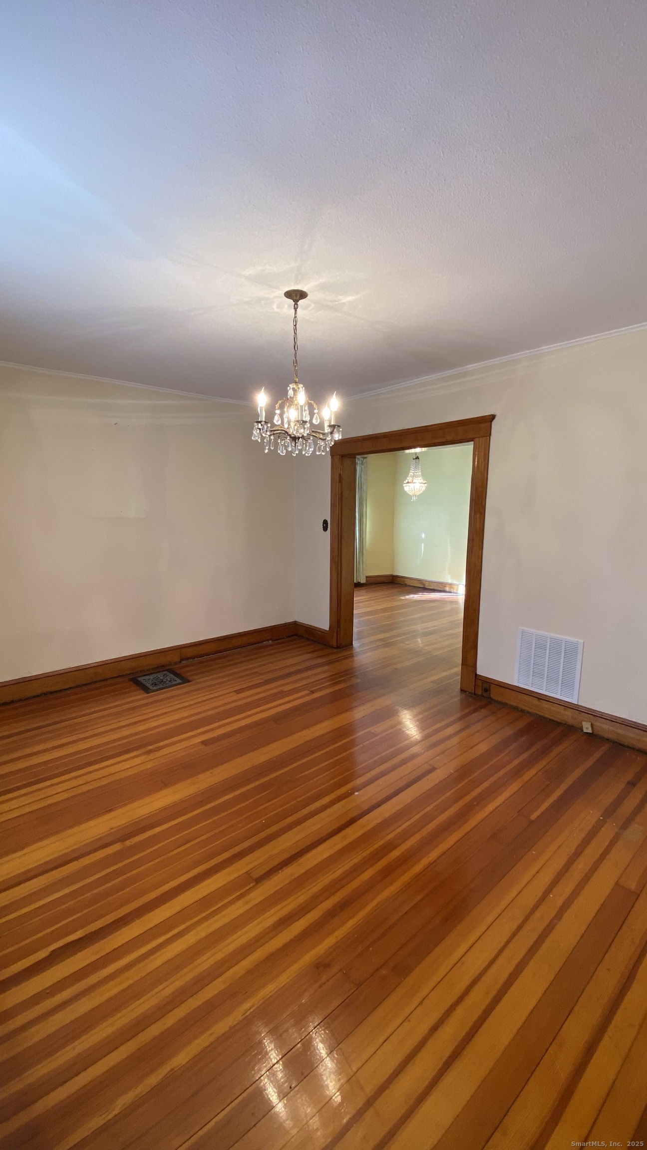 135 Elm Street, Unit 1 Winsted, CT 06098 - Photo 13 of 32 an empty room with wooden floor chandelier fan and windows