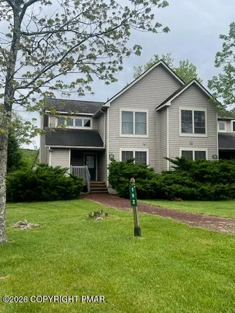 a front view of a house with a yard and trees