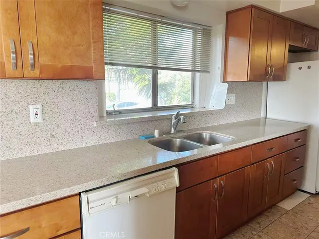 a kitchen with stainless steel appliances wooden cabinets a sink and a large window