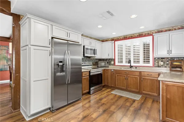 a kitchen with granite countertop stainless steel appliances a refrigerator cabinets and a window