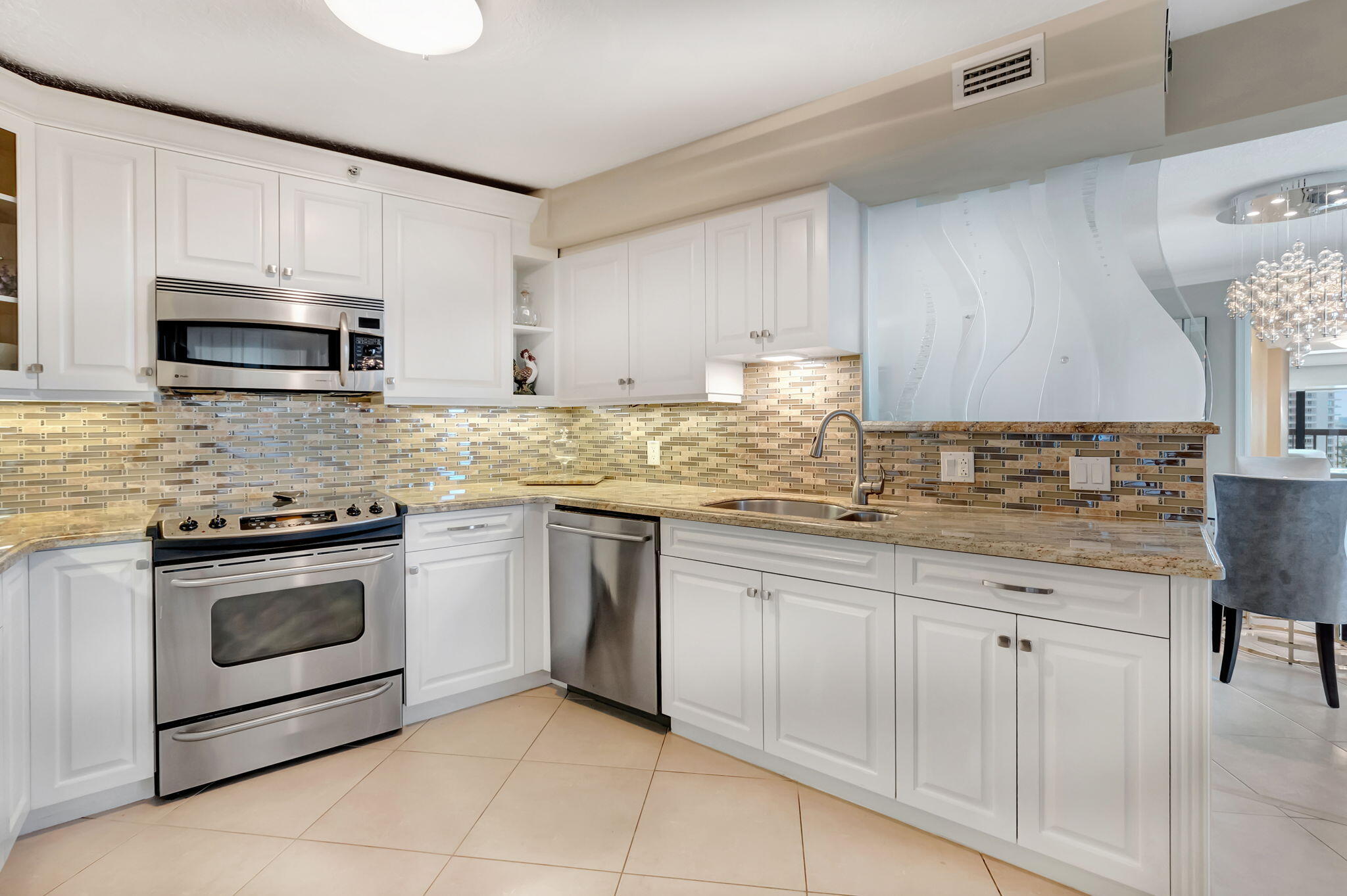 4545 North Ocean Boulevard, Unit 11C Boca Raton, FL 33431 - Photo 22 of 58 a kitchen with granite countertop white cabinets stainless steel appliances and a sink