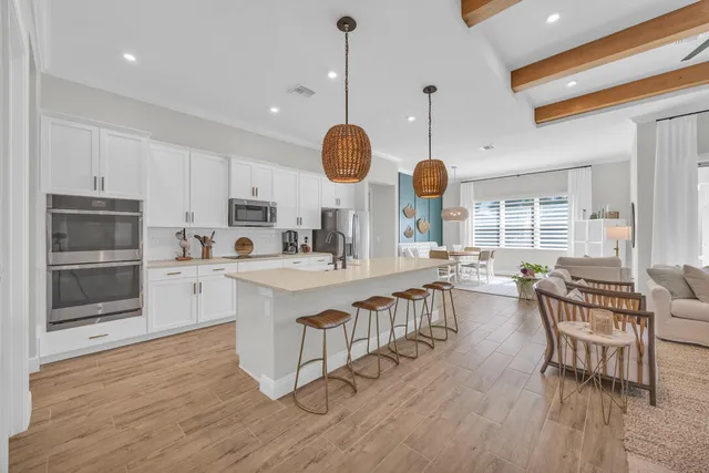 a kitchen with stainless steel appliances granite countertop a stove oven a dining table and chairs with wooden floor