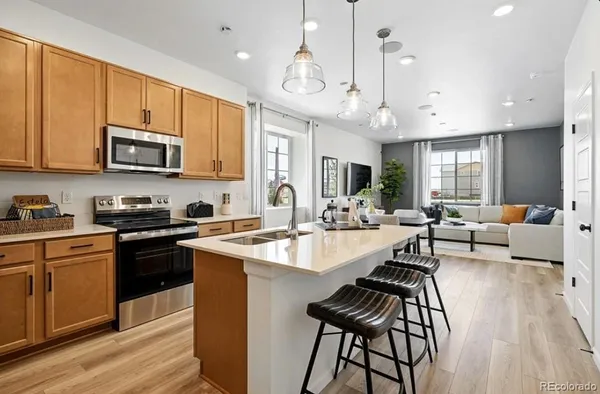 a kitchen with stainless steel appliances granite countertop a sink stove refrigerator and cabinets