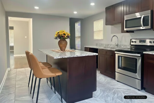 a kitchen with stainless steel appliances granite countertop a stove a sink a microwave a dining table and chairs