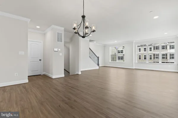 a view of an empty room with wooden floor and windows
