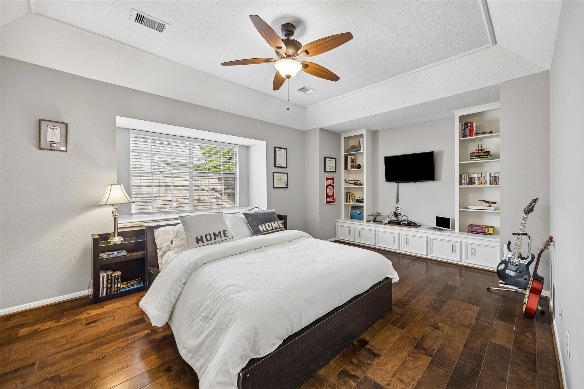 146 Golden Shadow Circle Spring, TX 77381 - Photo 32 of 41 This generously sized secondary bedroom features engineered hardwood flooring, a tray ceiling, and custom built-in cabinetry. A large window fills the room with natural light, creating a bright and inviting space with plenty of room to relax, study, or unwind.