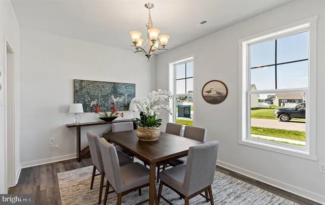 a dining room with chandelier and wooden floor