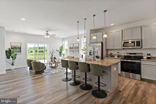 a kitchen with stainless steel appliances granite countertop a stove a sink dishwasher a dining table and chairs with wooden floor