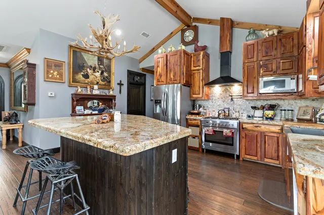 a kitchen with stainless steel appliances granite countertop a kitchen island a stove a table and chairs in it