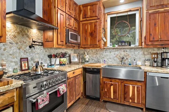 a kitchen with stainless steel appliances granite countertop a stove a sink and a microwave