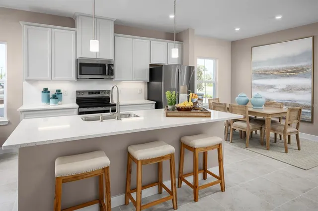 a kitchen with stainless steel appliances granite countertop a table chairs microwave and sink