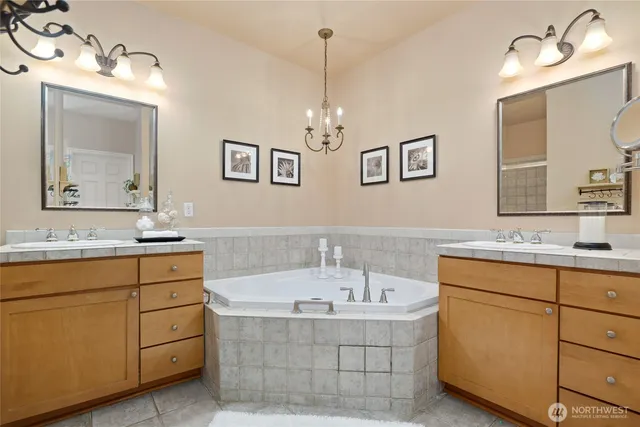 a bathroom with a tub sink double vanity and mirror