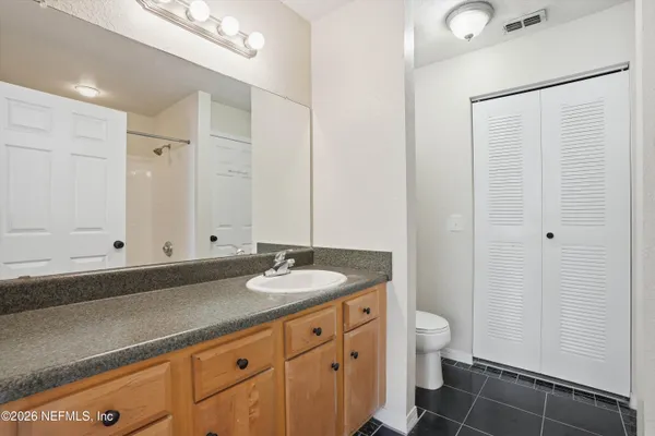 a bathroom with a granite countertop sink a toilet and a shower