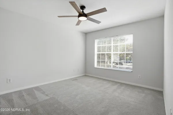 an empty room with a window and a fan