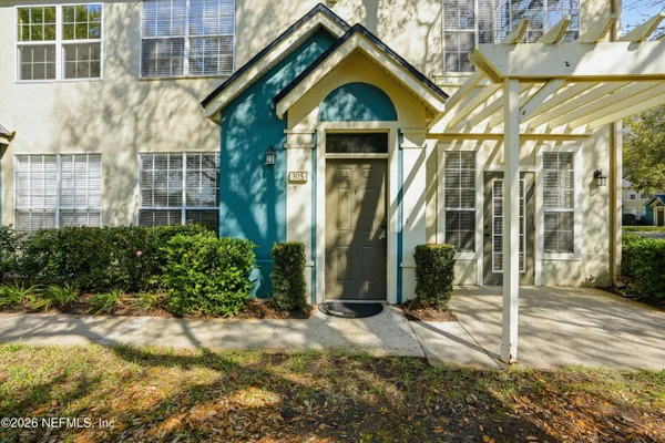 a view of a house with a small yard and potted plants