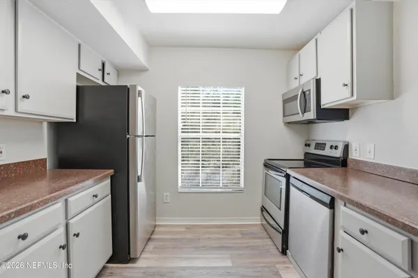 a kitchen with stainless steel appliances white cabinets and a refrigerator