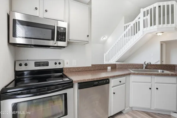 a kitchen with granite countertop a stove microwave and sink