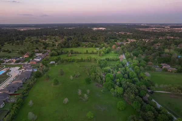 an aerial view of residential houses with outdoor space and trees