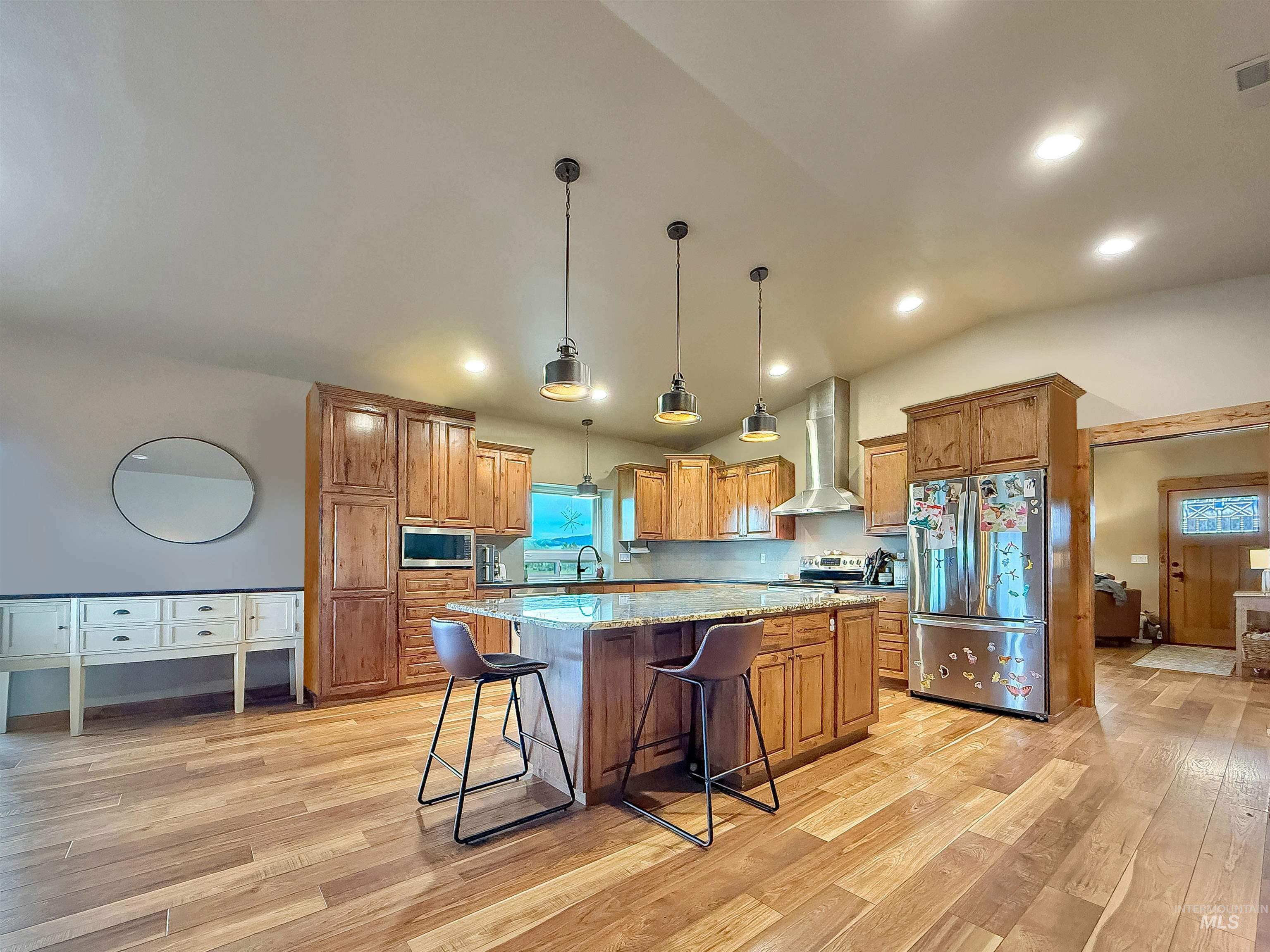1030 Tempest Lane Viola, ID 83872 - Photo 6 of 37 Kitchen featuring light stone countertops, wood finish cabinetry, stainless steel appliances, a center island, and vaulted ceiling