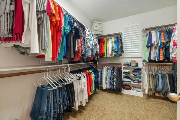 a view of walk in closet with clothes and shoes