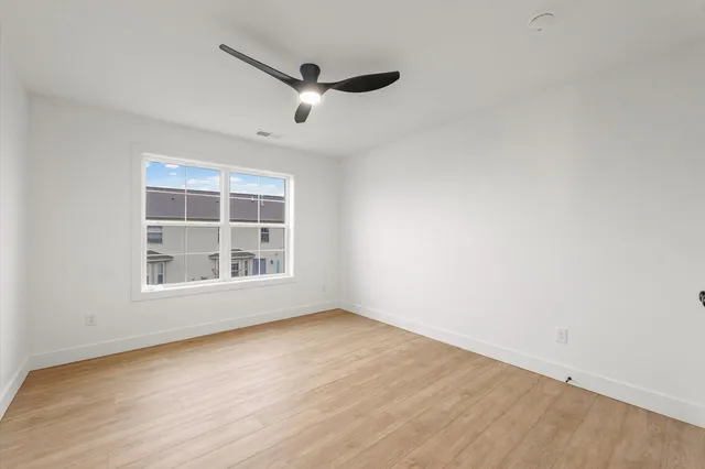 an empty room with wooden floor cabinet and windows