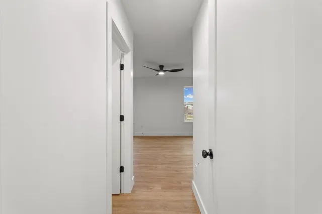 an empty room with wooden floor a ceiling fan and windows