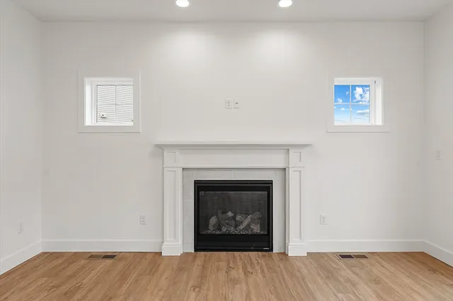 a view of an empty room with wooden floor and a fireplace